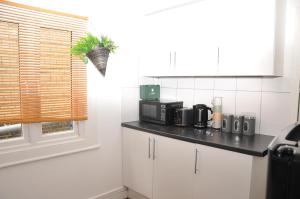 a kitchen with white cabinets and a black counter top at Virtue House in Woolwich