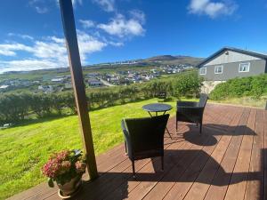 a patio with a table and chairs on a deck at Hyggelig lejlighed ved åen - flot udsigt in Tórshavn
