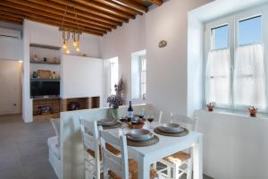 a white dining room with a white table and chairs at Tholos Guest House in Sifnos