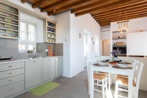 a kitchen with white cabinets and a white table and chairs at Tholos Guest House in Sifnos