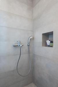 a shower with a hose in a bathroom at Tholos Guest House in Sifnos