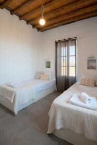 Tholos Guest House في Sifnos: سريرين في غرفة بجدران بيضاء