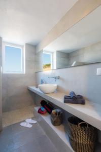 Tholos Guest House في Sifnos: حمام مع حوض ومكتب مع مرآة