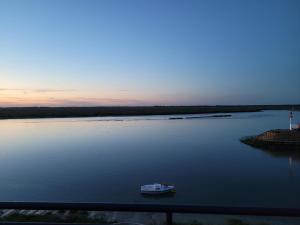 łódź na środku rzeki z latarnią morską w obiekcie Vue et terrasse panoramique sur la Baie de Somme w mieście Saint-Valéry-sur-Somme