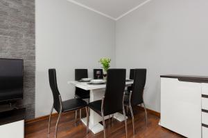comedor con mesa blanca y sillas negras en Business Apartments Warsaw Wola Kasprzaka by Renters en Varsovia