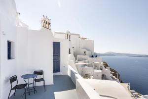 a balcony with chairs and a table overlooking the ocean at Oia Cave Loft in Oia