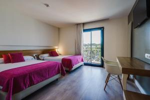 um quarto de hotel com duas camas e uma varanda em Hotel Brisamar Suites em Comarruga