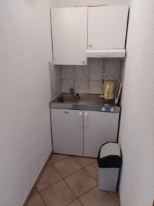 a small kitchen with white cabinets and a sink at Apartments Menalo in Neum