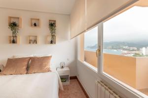 een slaapkamer met een bed en een groot raam bij Apto con vistas al mar GURE IZARRA en Bakio By Kabia Gestión in Bakio
