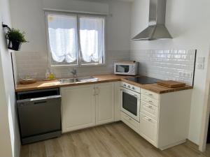kuchnia z białymi szafkami, zlewem i kuchenką mikrofalową w obiekcie DOMUS AUREA Maison Dorée w mieście Jard-sur-Mer +6 zdjęć