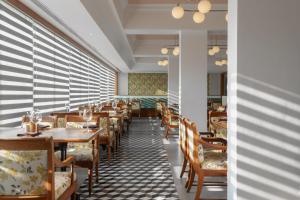 a restaurant with wooden tables and chairs and blinds at The Avenue Regent in Cochin