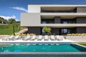 eine Villa mit einem Pool vor einem Haus in der Unterkunft Oltremare apartments with pool in Rabac
