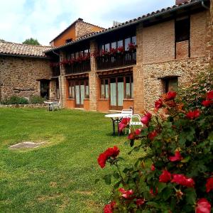 un edificio con una mesa y rosas en el patio en Mas Cal Sastre, en Sant Hilari Sacalm