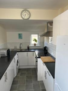 una cocina con armarios blancos y un reloj en la pared en Comfortable King Bed - Location - Contractors - Family - Parking en Bedford