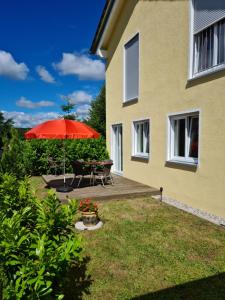 a patio with a table and a red umbrella at Apartment Gästehaus Staudenschloß in Mickhausen