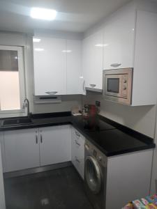 a kitchen with white cabinets and a washing machine at apartamento COLON !!PARKING PRIVADO GRATUITO !! in Logroño