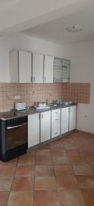 kuchnia z białymi szafkami i czarnym piecem w obiekcie Villa Dobra Family Apartments w mieście Vir