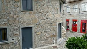 ein Steingebäude mit roten Türen und Fenstern in der Unterkunft Casa do Pelourinho - T0 in Loriga