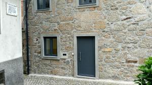 un edificio in pietra con una porta e due finestre di Casa do Pelourinho - T0 a Loriga