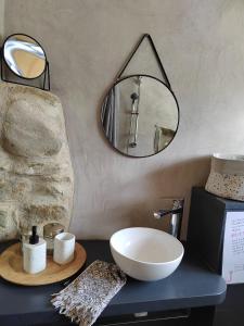 La salle de bains est pourvue d'un lavabo et d'un miroir sur un comptoir. dans l'établissement Le Mas Bellane, à Salettes