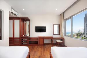 Schlafzimmer mit einem Schreibtisch, einem TV und einem Fenster in der Unterkunft Sekong Hotel Da Nang in Đà Nẵng