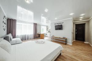 a white bedroom with a white bed and a tv at Квартира-студия в центре Публика in Petropavlovsk