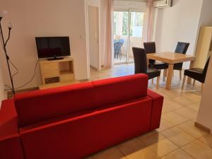 sala de estar con sofá rojo y TV en Appartement T2 dans résidence avec piscine, en Moriani Plage