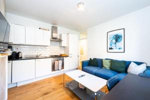 a living room with a blue couch and a kitchen at Pass the Keys Stay Central in Sunny Waterloo Apartment in London