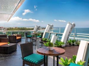 een balkon met tafels en stoelen en de oceaan bij The Kuta Beach Heritage Hotel - Managed by Accor in Kuta