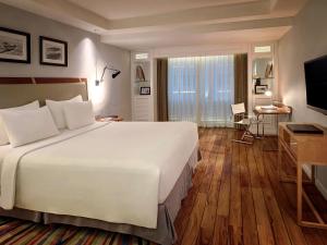 una camera d'albergo con un grande letto e una TV di The Kuta Beach Heritage Hotel - Managed by Accor a Kuta