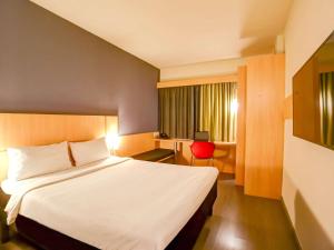 リオデジャネイロにあるイビス RJ ノヴァ アメリカ ホテルのベッドルーム1室(大型ベッド1台、赤い椅子付)