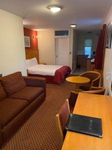 a hotel room with a bed and a couch and tables at The Tudor Hotel in Harrow