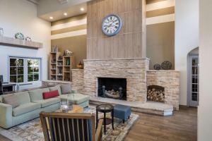 a living room with a fireplace with a clock on the wall at MainStay Suites John Wayne Airport, a Choice Hotel in Santa Ana