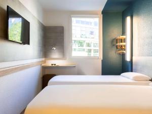a bedroom with a white bed and white walls at ibis budget Porte D'Orleans in Paris