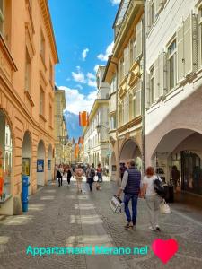 um grupo de pessoas andando por uma rua com edifícios em Portico 32 - Merano centro em Merano