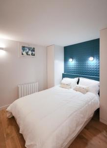 - une chambre avec un grand lit blanc et une tête de lit bleue dans l'établissement L'élégant de fourvière, à Lyon