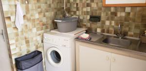een kleine keuken met een wasmachine en een wastafel bij Gîte indépendant in Caux-et-Sauzens