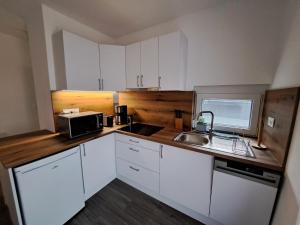 a kitchen with white cabinets and a sink and a microwave at Villa Field6 in Révfülöp