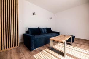 sala de estar con sofá azul y mesa de madera en Apartamenty Henry, en Łeba