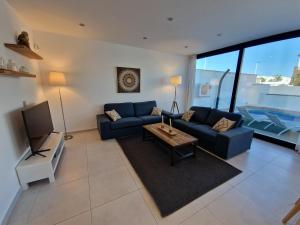 a living room with a blue couch and a tv at Lo Pagan Holiday House in San Pedro del Pinatar