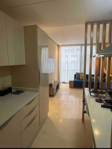 a kitchen with white cabinets and a living room at Cosy appartement à Ain Diab beach in Casablanca