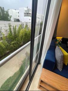 a room with a window with a blue couch next to it at Cosy appartement à Ain Diab beach in Casablanca