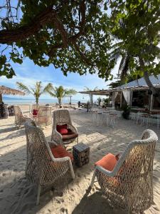 a group of chairs and tables on the beach at Sabaii Bay Resort in Ban Tai