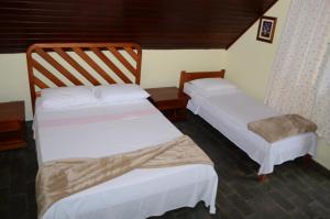 two beds sitting in a room with at Pousada Chalés da Estalagem in São Bento do Sapucaí