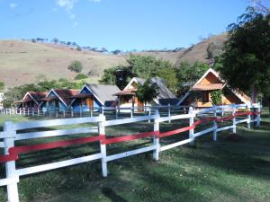 a white fence in front of a group of houses at Pousada Chalés da Estalagem in São Bento do Sapucaí