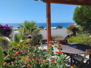 een patio met een tafel en bloemen en de oceaan bij Beautiful small bungalow, amazing views and garden in Famara