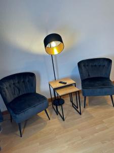 duas cadeiras e uma mesa e um candeeiro num quarto em Jade FeWo Cottbus em Cottbus