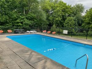 une grande piscine bleue avec une table de pique-nique et des chaises dans l'établissement La Paysanne Motel & Hotel, à Sherbrooke