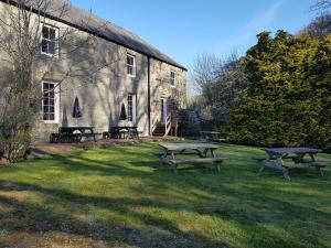 un grupo de mesas de picnic frente a un edificio en Redesdale Arms en Otterburn