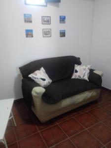 a black couch sitting in a corner of a room at Casas da Saibreira - nº10 in Elvas